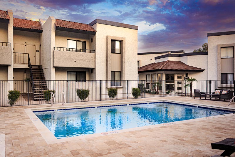 Residential community pool surrounded by apartment buildings at sunset.